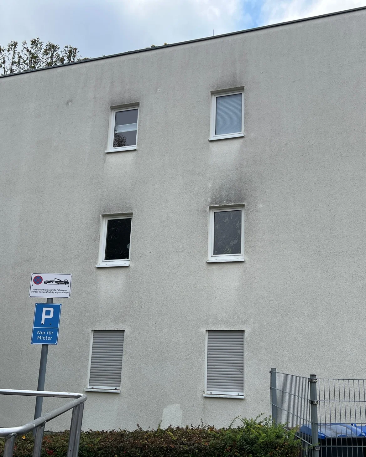 Mehrfamilienhaus mit dunklen Algenstreifen unter den Fenstern vor der Reinigung
